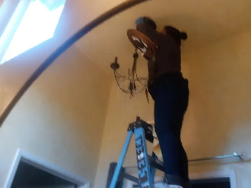 Electrician installing a chandelier in a Oak Forest residence